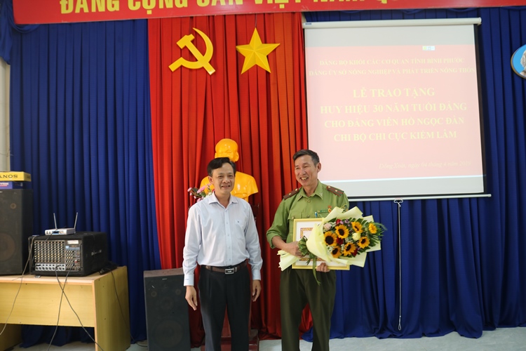 Đ/c Lê Anh Nam - PBT Đảng ủy Sở trao Huy hiệu 30 năm tuổi Đảng và hoa cho đ/c Hồ Ngọc Đàn